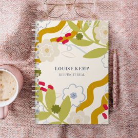 Flowers blooming wiro bound diary on a pink blanket with a cup of coffee and a pen